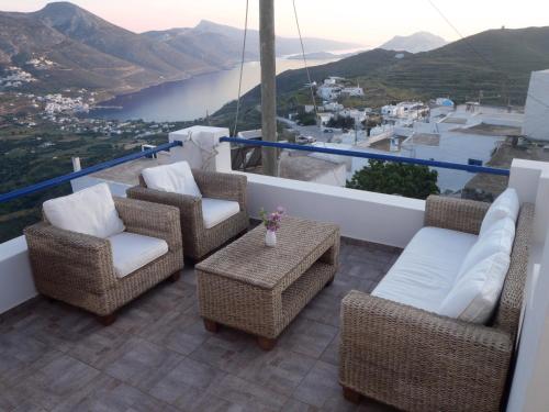 a balcony with wicker chairs and a table with a view at Plori Studios and Apartments in Aegiali