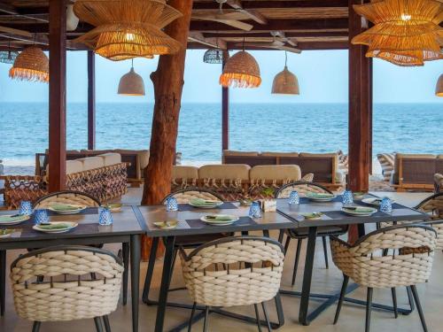 a dining room with a table and chairs and the ocean at SO/ Sofitel Hua Hin in Cha Am