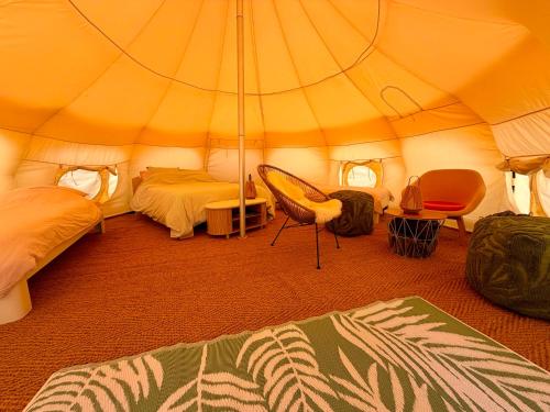 a bedroom with a tent with two beds and a chair at Nest Lodge in Weissbriach