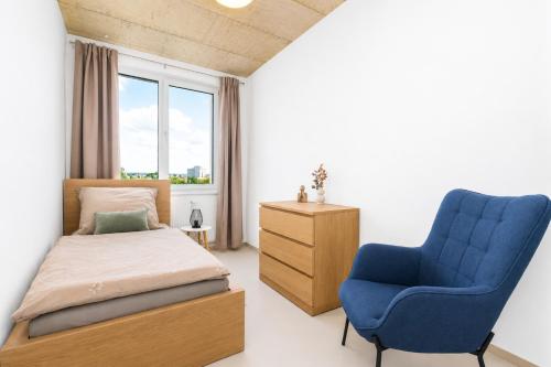 a bedroom with a bed and a blue chair at Apartmány Gočárova třída in Hradec Králové