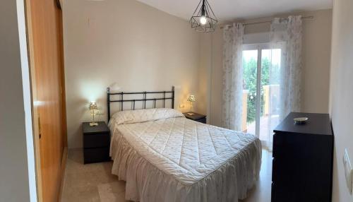 a bedroom with a bed with two night stands and a window at A spacious apartment with an ocean view in Mijas Costa
