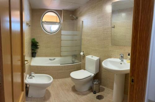 a bathroom with a toilet and a sink and a tub at A spacious apartment with an ocean view in Mijas Costa
