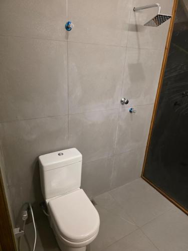a small bathroom with a toilet and a shower at The Shenu Lake House in Dandugama