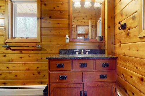 a bathroom with a sink and a wooden wall at Mountain View Chalet in West Dover