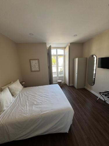 a hotel room with a white bed and a refrigerator at Casa da Praça- Boutique Rooms in Tavira