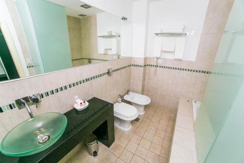 uma casa de banho com um lavatório verde e um WC em Amérian Villa Maria Park Hotel em Villa María