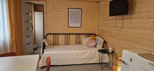 a small bedroom with a bed and a television at Niezła Szopka domki nad jeziorem in Nowe Guty