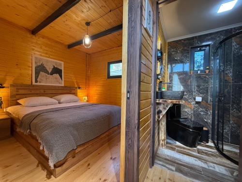 a bedroom in a log cabin with a bed and a fireplace at West Coast Cottage Buknari in Buknari