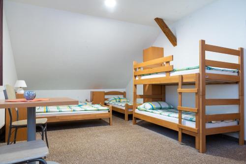a room with three bunk beds and a table at Hostel 1550 in Moravske-Toplice