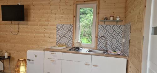 a kitchen with a sink and a window at Niezła Szopka domki nad jeziorem in Nowe Guty
