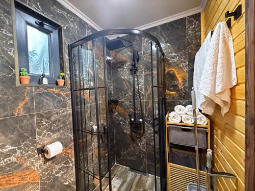 a shower with a glass door in a bathroom at West Coast Cottage Buknari in Buknari