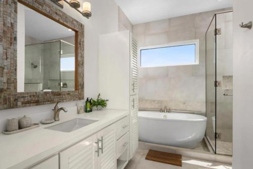 a bathroom with a tub and a sink and a mirror at Second Wind Villa in Long Bay Hills