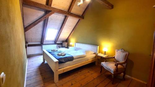 a bedroom with a bed and a chair and a window at Ferienwohnung Blauregen - NEU ab März 2026 in Hohnstein