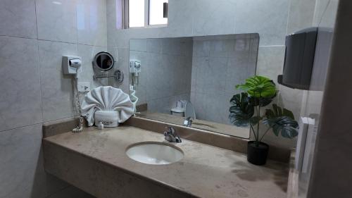 a bathroom with a sink and a mirror at Hotel Maioris Kumate Culiacán in Culiacán