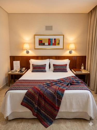 ein Hotelzimmer mit einem großen Bett mit zwei Tischen in der Unterkunft Hotel Riviera in Sao Jose do Rio Preto