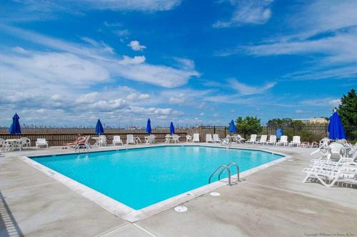 a swimming pool with lounge chairs and umbrellas at Bay Princess 103 in Ocean City