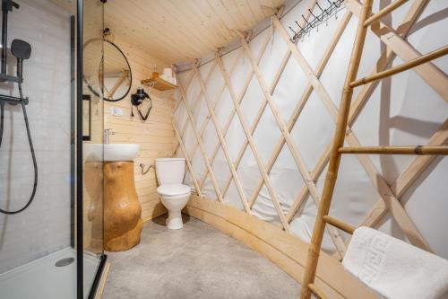 ein Badezimmer mit einer Toilette in einer Holzwand in der Unterkunft Aloha Glamp - Całoroczny glamping nad rzeką z prywatną balią - Stok narciarski, góry, lasy, sauna in Zagórnik