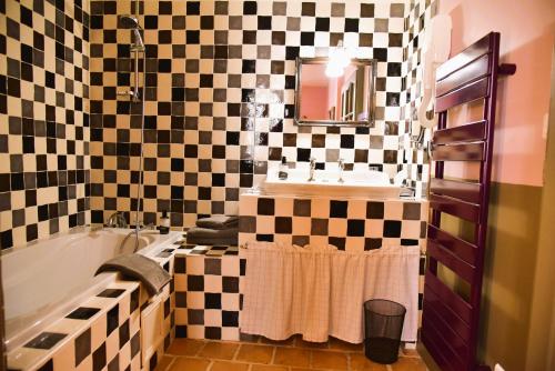 a bathroom with a black and white checkered wall at Logis Hôtel Le Boudoir in Belvès