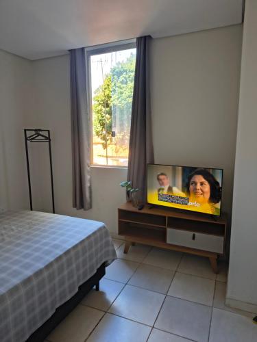 ein Schlafzimmer mit einem Fernseher auf einem Tisch und einem Bett in der Unterkunft Kitnet NOMAD in Barão de Cocais