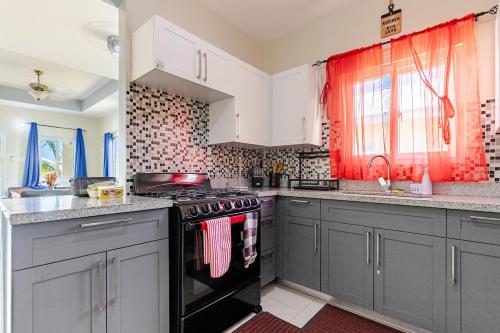 a kitchen with gray cabinets and a stove top oven at Hamilton @ Oceanpointe a serene 2bed 2 bath Villa in Lucea