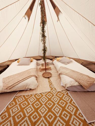 a tent with two beds and a rug in it at La Belle Verte in Laruscade