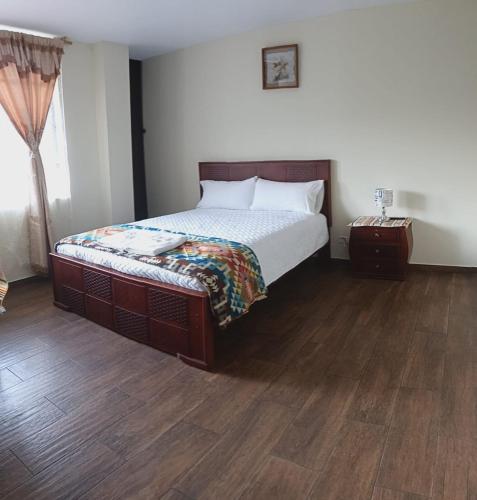 a bedroom with a bed and a wooden floor at Hostería en Chachimbiro - Ariq in Hacienda San Francisco