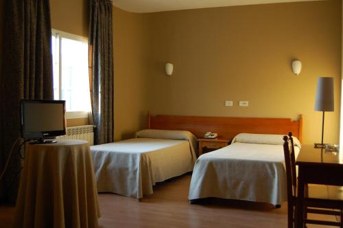 a hotel room with two beds and a television at Hotel París in Poio