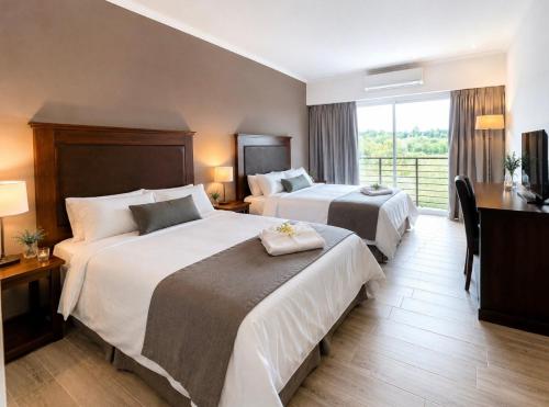 a hotel room with two beds and a balcony at Hotel Cardal Tandil in Tandil