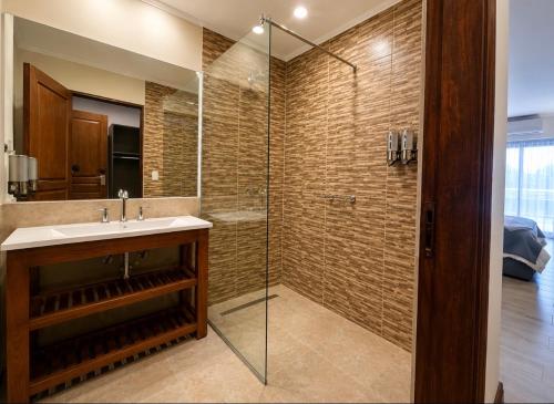 a bathroom with a sink and a glass shower at Hotel Cardal Tandil in Tandil