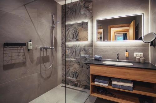 a bathroom with a shower and a sink and a mirror at Appartementhaus Bergkristall in Kartitsch