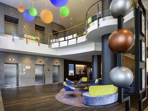 a lobby with chairs and a table and a staircase at Mercure Hotel Bochum City in Bochum