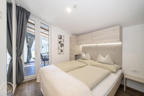 a white bedroom with a large bed and a balcony at Possegger Hideaways in Zödl