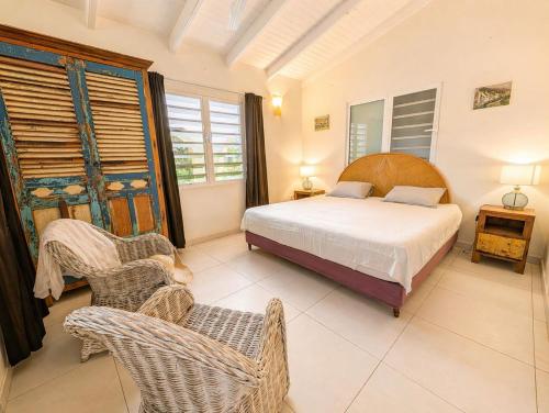 a bedroom with a bed and chairs in a room at 30 Kas Di Mi Sonjo in Kralendijk