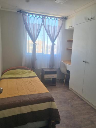 a bedroom with a bed and a window with a desk at Dpto santa rosa in Ovalle