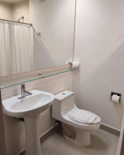 a bathroom with a sink and a toilet and a mirror at Hotel Lois Express Monterrey Aeropuerto La Fe in Monterrey