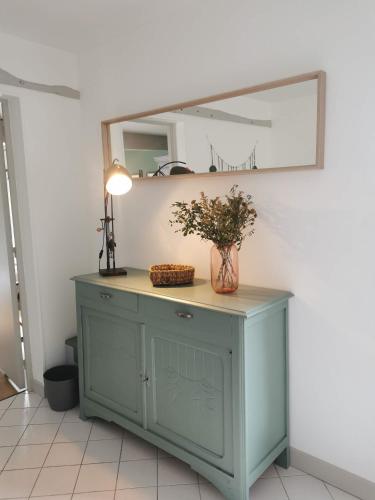 a blue cabinet with a mirror on a wall at La petite FloPée in Le Mont-Saint-Adrien