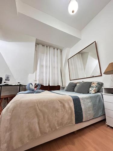 a bedroom with a bed with a desk and a mirror at Lofts aconchegantes no Palácio Quitandinha in Petrópolis