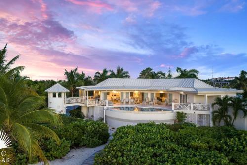 a villa with a swimming pool in front of a house at Turtle Beach 5BR Snorkeling Kayaks & Family Entertainment in Providenciales