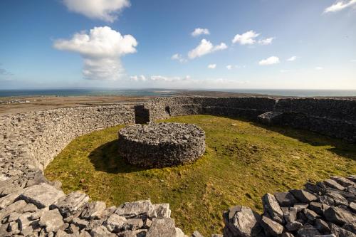 an old stone wall with the ocean in the background at Aran Islands Hotel in Kilronan