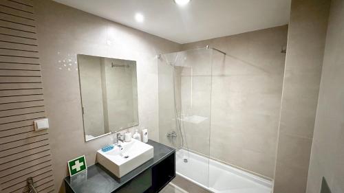 a bathroom with a sink and a shower and a mirror at The Surf - Rocha Tower in Portimão