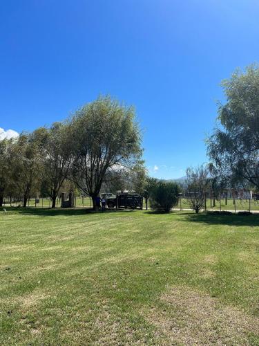 a large grass field with trees in the background at Rest has name Sonko in Tafí del Valle