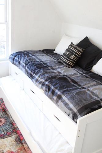 a white bed with black blankets and pillows on it at The Polished Plank in Kokomo