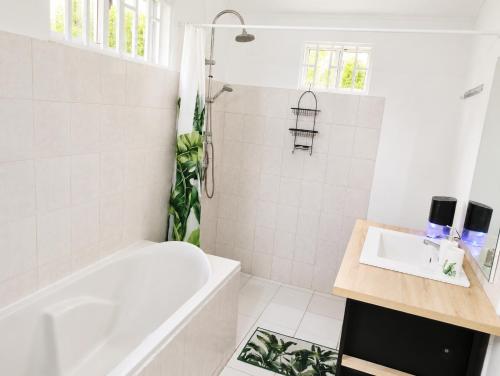 a white bathroom with a tub and a sink at La villa fruitier Cavalier in Saint-Laurent du Maroni