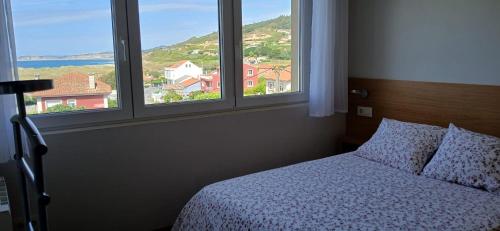 a bedroom with a bed and two windows with a view at Barrañán Arena in Arteixo
