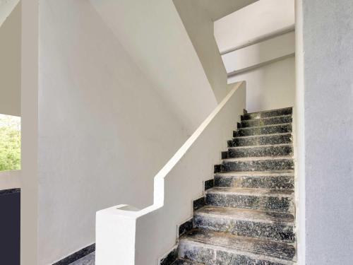 a staircase in a house with white walls at Hotel O Hills Land in Warangal