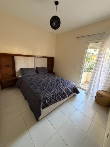 a bedroom with a bed and a window at Superbe Appartement Bord de mer in Bouznika