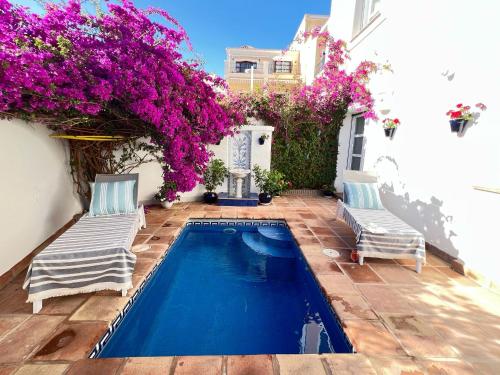 a swimming pool with two chairs and purple flowers at VILLA AMIRA ,Marbella Estepona in Benahavís