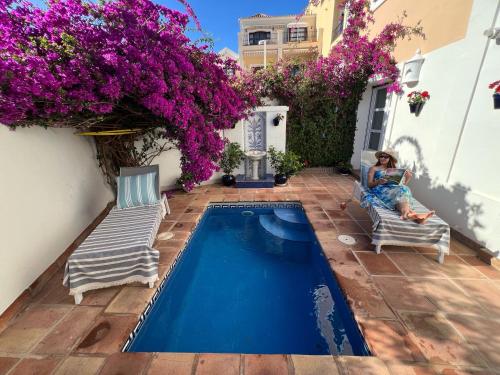 a woman sitting on a chair next to a swimming pool at VILLA AMIRA ,Marbella Estepona in Benahavís