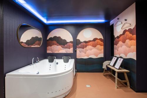 a bath tub in a room with paintings on the wall at Doux Pavillon - 1001 nuits - Jaccuzi in Mulhouse