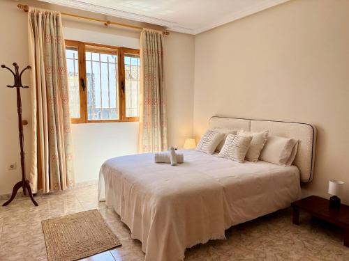 a bedroom with a large white bed with a window at La terraza del Campanario in Ríolobos